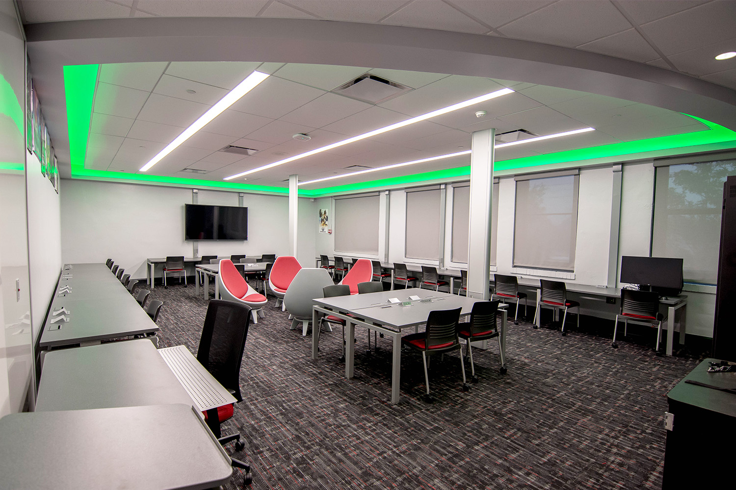 Andrew Jackson High game design lab with green LED lights in the ceiling, wall mounted media displays and desks