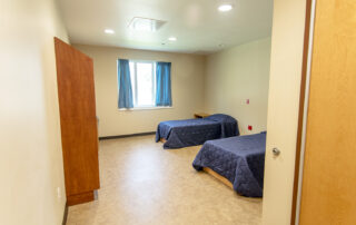 Blackberry Center patient room with two beds, a window, desk and clothes dresser